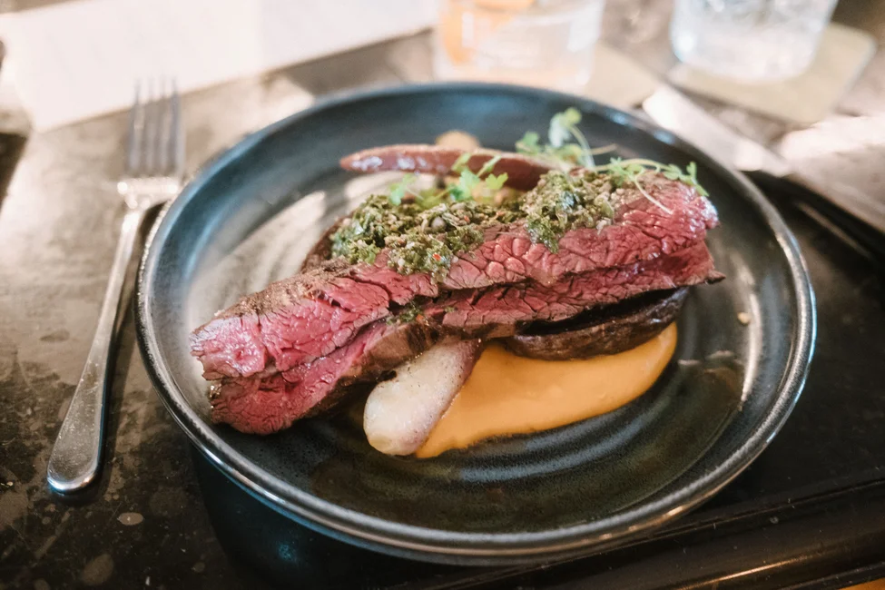 Corte de carne con chimichurri en presentación de alta cocina. Imagen ilustrativa genérica (banco de imágenes Pexels, foto: Deane Bayas) — no corresponde a un plato de Fogón Asado.
