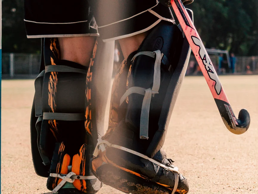 Arquero de hockey sobre césped con sus elementos de protección y el palo, en una cancha al aire libre (foto: Luis Baez / Pexels; imagen ilustrativa de la disciplina)