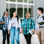 Grupo de estudiantes universitarios caminando y riendo en un campus (imagen ilustrativa genérica, banco de imágenes Pexels)