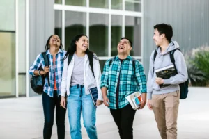 Grupo de estudiantes universitarios caminando y riendo en un campus (imagen ilustrativa genérica, banco de imágenes Pexels)