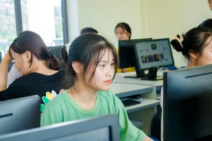 Estudiantes trabajando en computadoras de escritorio en un aula (imagen ilustrativa genérica, banco de imágenes Pexels)