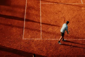 Jugador de tenis en pose de saque sobre cancha de polvo de ladrillo (imagen ilustrativa genérica; foto: Gera Cejas / Pexels)