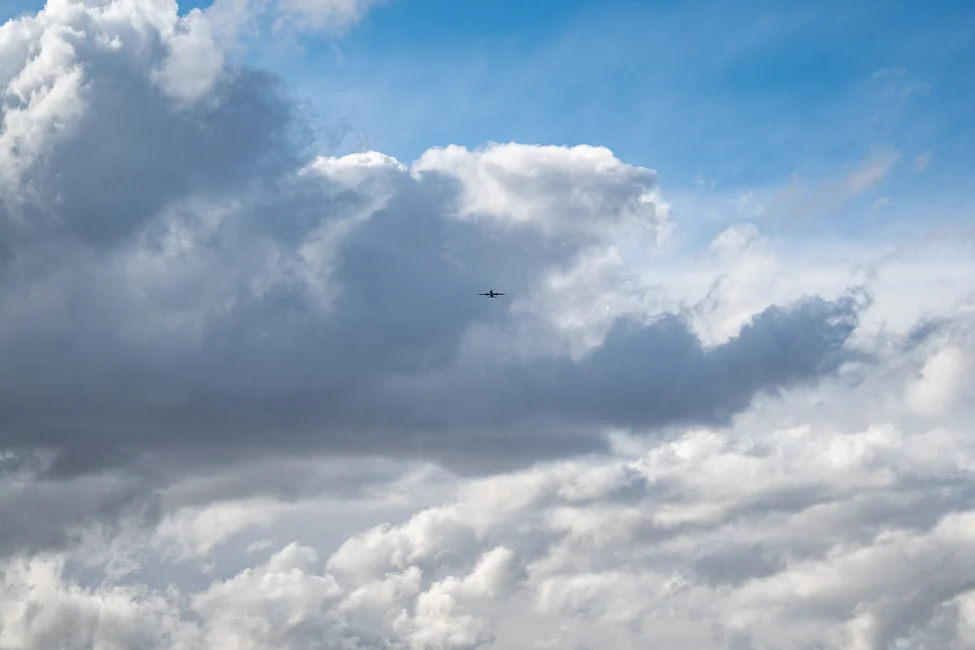 Un avión visto a la distancia entre nubes. Imagen ilustrativa genérica de aviación, banco de imágenes Pexels (fotógrafo: Brett Sayles).