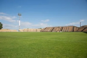 Estadio de fútbol vacío con tribunas y reflectores bajo cielo despejado, imagen ilustrativa genérica (no es el Kempes de Córdoba). Pexels / Kampus Production.