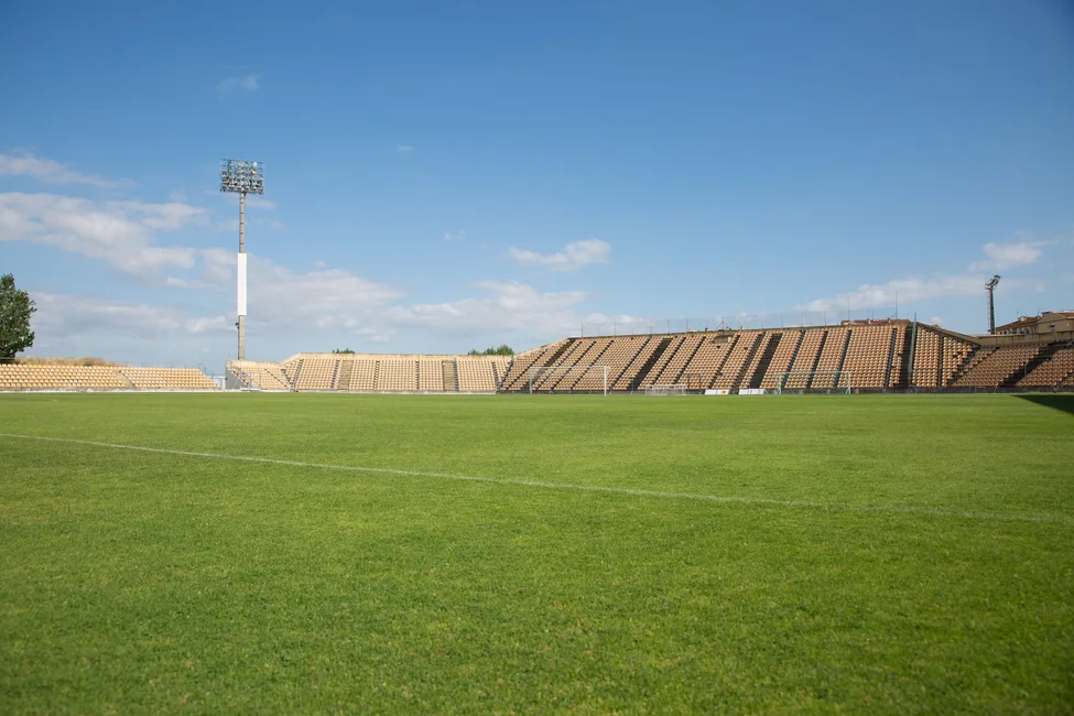 Estadio de fútbol vacío con tribunas y reflectores bajo cielo despejado, imagen ilustrativa genérica (no es el Kempes de Córdoba). Pexels / Kampus Production.